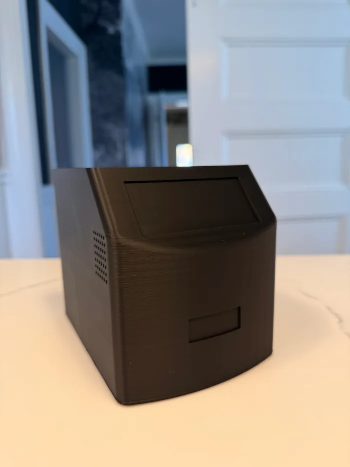 Edison Popcorn printed in black, sitting on a kitchen counter: an angled screen panel on top, a speaker grille on the side and a cartridge slot in the curved front
